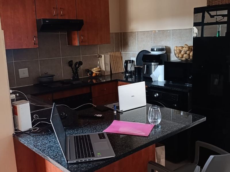 A functional kitchen featuring dark granite countertops, wood-finish cabinetry, a tiled backsplash, and an integrated breakfast bar area.