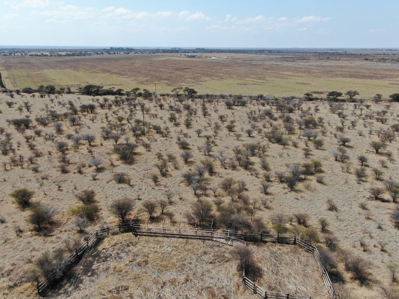 Aerial view of a large vacant residential plot featuring native vegetation and a wooden livestock enclosure.