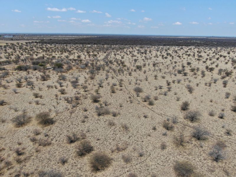 An aerial view of a large, undeveloped residential land plot featuring native vegetation and open terrain.