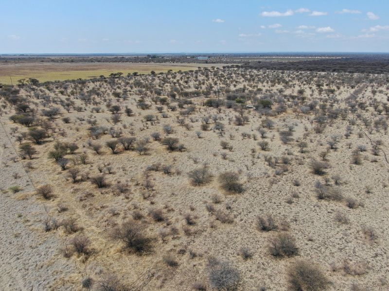 An aerial view of a large, undeveloped residential land parcel featuring native scrub vegetation and perimeter fencing.