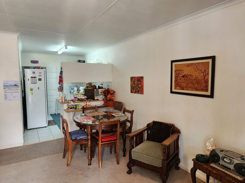 Open plan living and dining area featuring a compact kitchen with breakfast bar and tiled flooring.