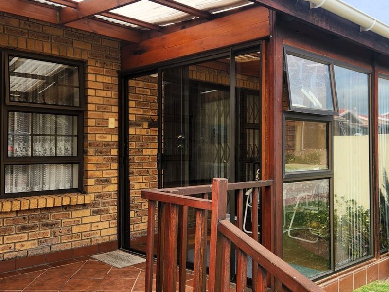 A covered patio area featuring a timber pergola, tiled flooring, and sliding glass doors providing access to the interior.