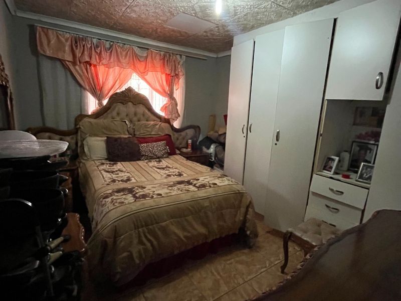 A bedroom featuring built-in cupboards, tiled flooring, and a decorative patterned ceiling.