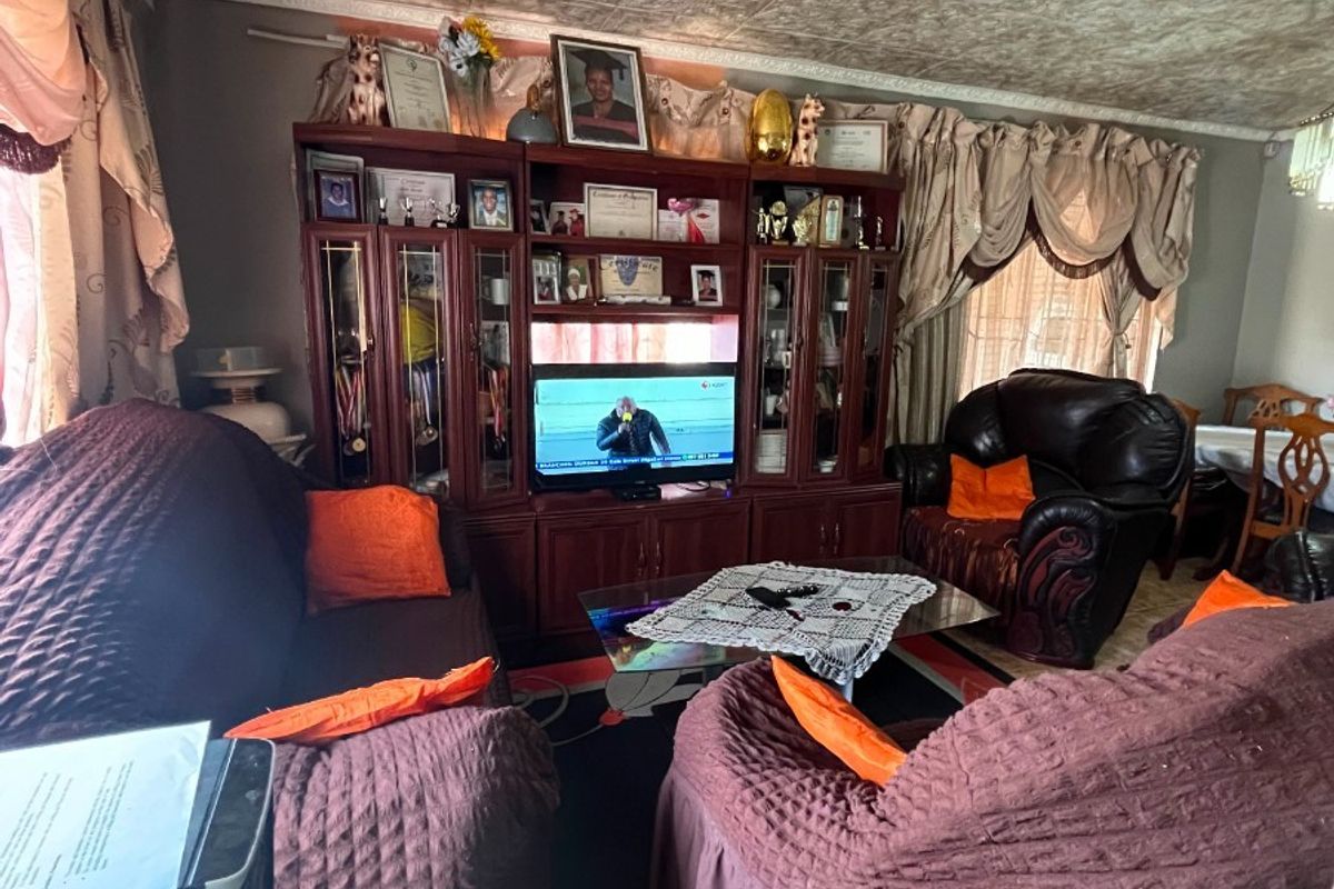 A living room featuring a built-in wall unit, textured ceiling tiles, and ceramic floor tiling, offering potential for modernization.