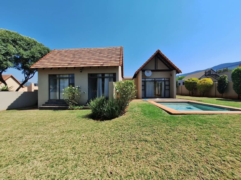 Rear view of the property featuring a well-maintained garden, a swimming pool, and a house with a tiled roof and sliding glass doors.