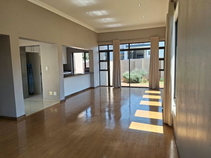 Spacious open-plan living area featuring polished laminate flooring, recessed lighting, and large sliding glass doors providing access to the rear garden.
