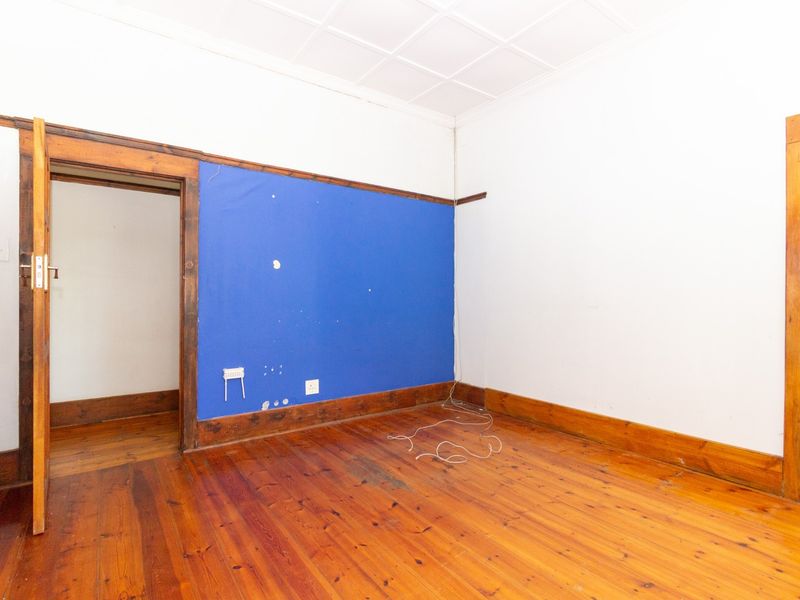 An empty office space featuring original timber flooring, wooden door frames, and a tiled ceiling, ready for renovation or custom fit-out.