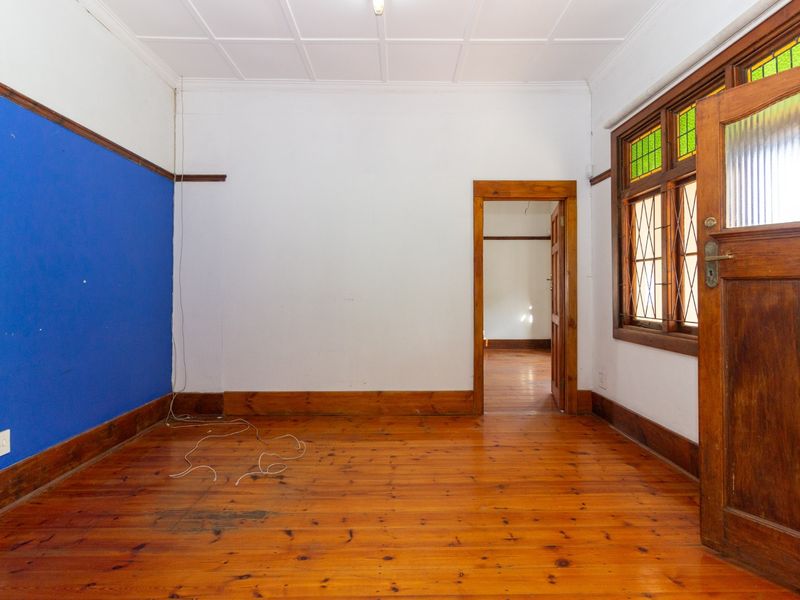 An empty office space featuring original timber flooring, stained glass windows, and classic timber door frames, offering a character-filled workspace.