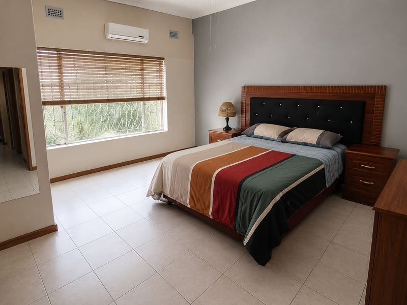 Spacious bedroom featuring tiled flooring, a split-system air conditioner, and large windows with security bars and venetian blinds.