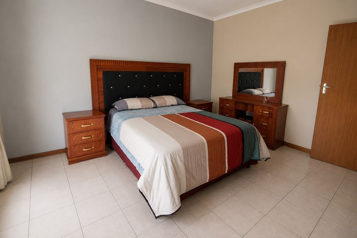 A well-maintained bedroom featuring neutral wall tones, tiled flooring, and classic cornice detailing, offering a clean and functional living space.
