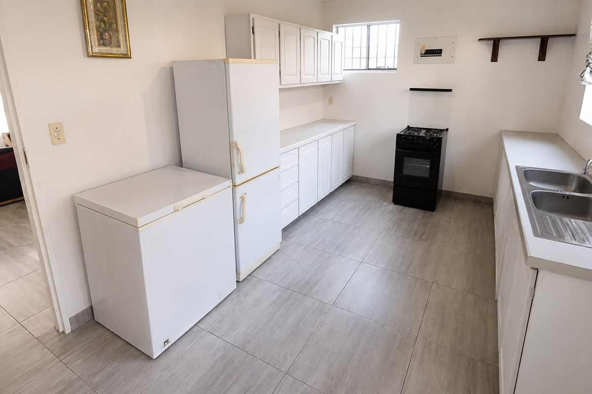 A functional kitchen featuring white cabinetry, tiled flooring, a double stainless steel sink, and a freestanding stove.