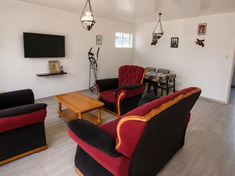 A functional living area featuring tiled flooring, tongue and groove ceiling, and security window bars, offering a neutral base for potential interior updates.