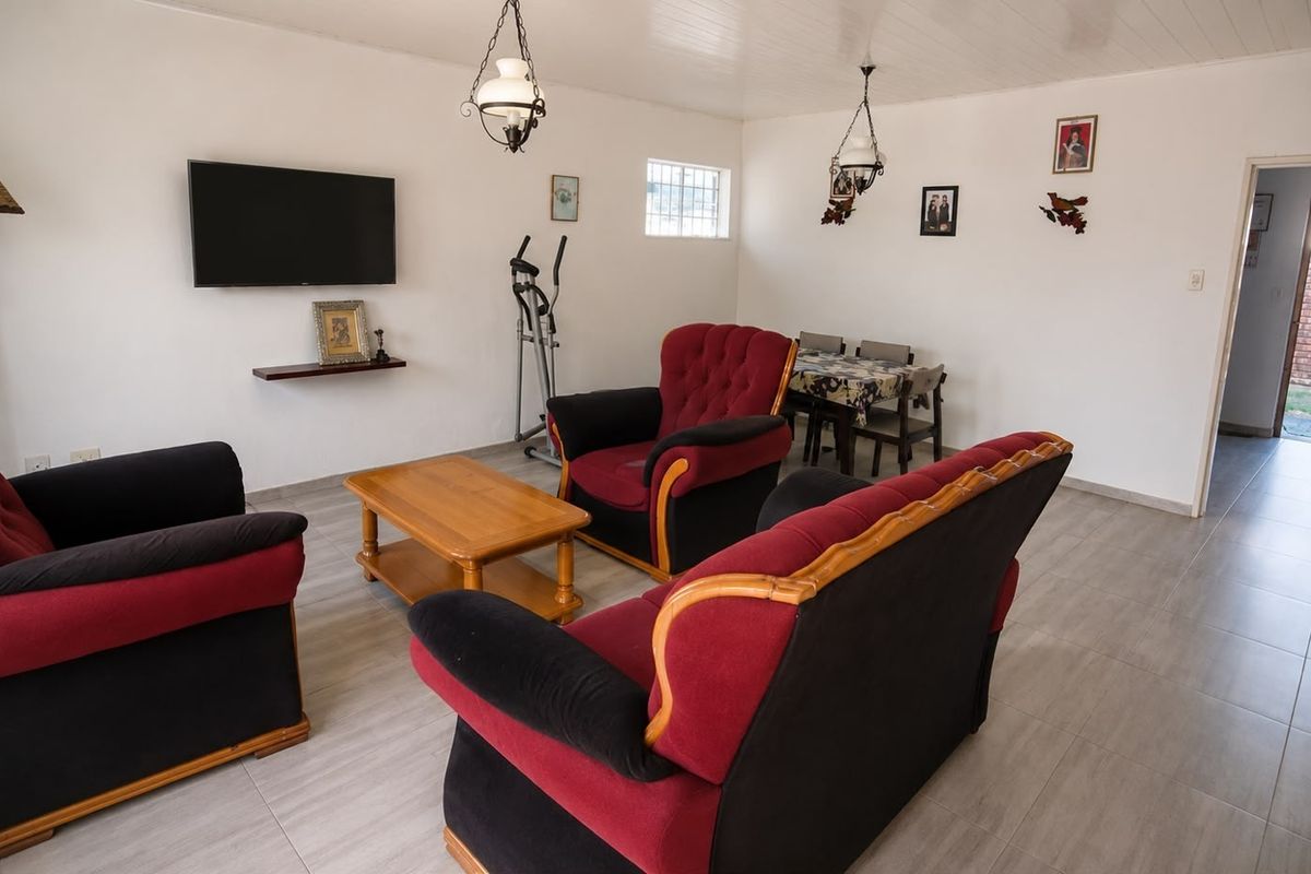 A functional living area featuring tiled flooring, tongue and groove ceiling, and security window bars, offering a neutral base for potential interior updates.