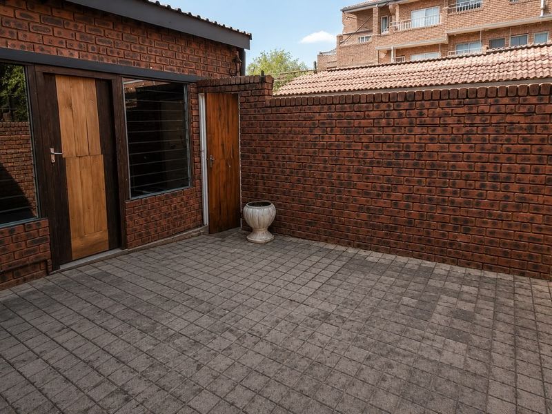 A private paved courtyard area featuring face brick walls and direct access to the property through timber doors.