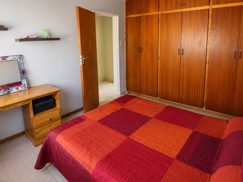 A bedroom featuring built-in wooden cupboards and tiled flooring, providing functional storage space.