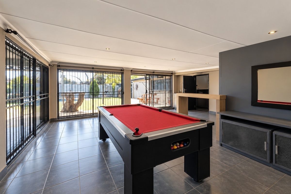 Spacious entertainment room featuring tiled flooring, recessed lighting, a built-in bar counter, and large sliding doors providing access to the outdoor area.