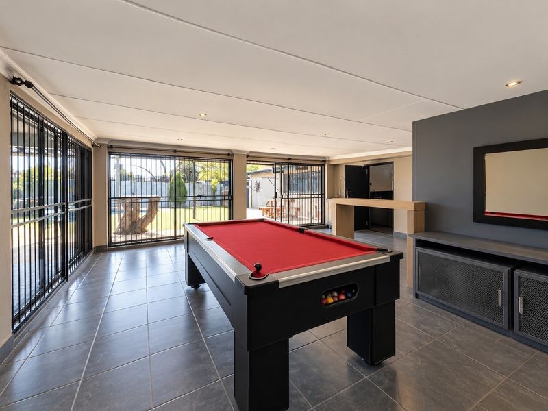 Spacious entertainment room featuring tiled flooring, recessed lighting, a built-in bar counter, and large sliding doors providing access to the outdoor area.