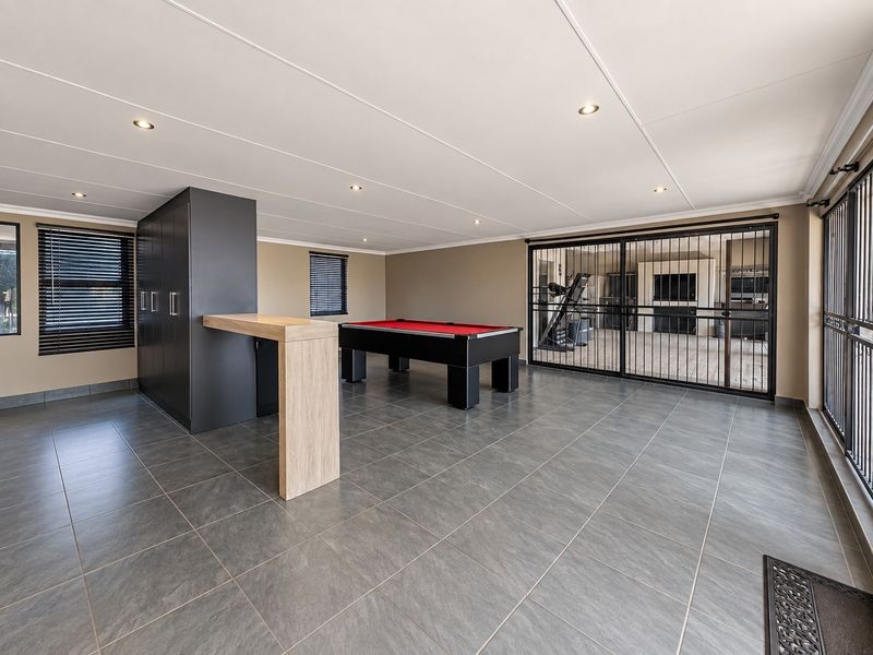 Spacious living area featuring large format floor tiles, recessed lighting, built-in cabinetry with a breakfast bar, and secure access to an adjacent outdoor space.