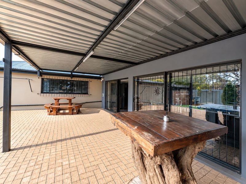 A spacious covered patio featuring paved flooring, a corrugated metal roof, and large sliding glass doors providing access to the interior.