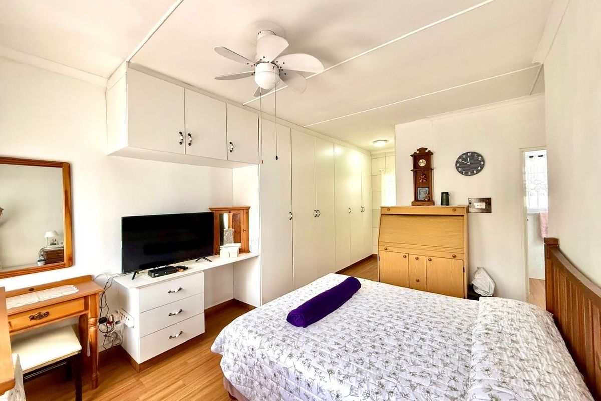 A bedroom featuring extensive built-in cupboards, overhead storage, a ceiling fan, and laminate flooring.