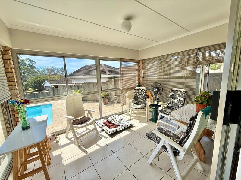 A bright, enclosed patio area featuring tiled flooring and large sliding glass doors that provide a view of the outdoor pool area.