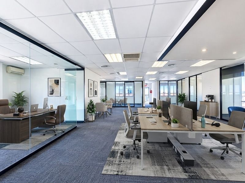 Modern open-plan office space featuring glass-partitioned private offices, suspended ceilings with recessed lighting, and high-quality carpeted flooring throughout.