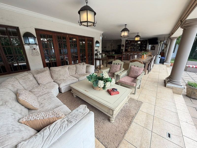 Spacious covered patio featuring tiled flooring, stone columns, and a built-in bar area, perfect for outdoor entertaining and relaxation.