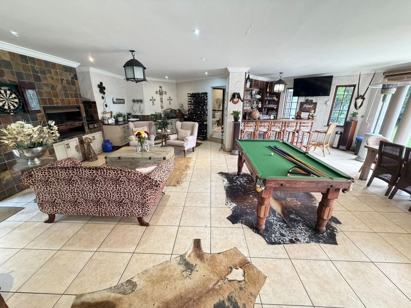 Spacious open-plan entertainment area featuring a built-in braai, a dedicated bar section, and tiled flooring, ideal for hosting and social gatherings.