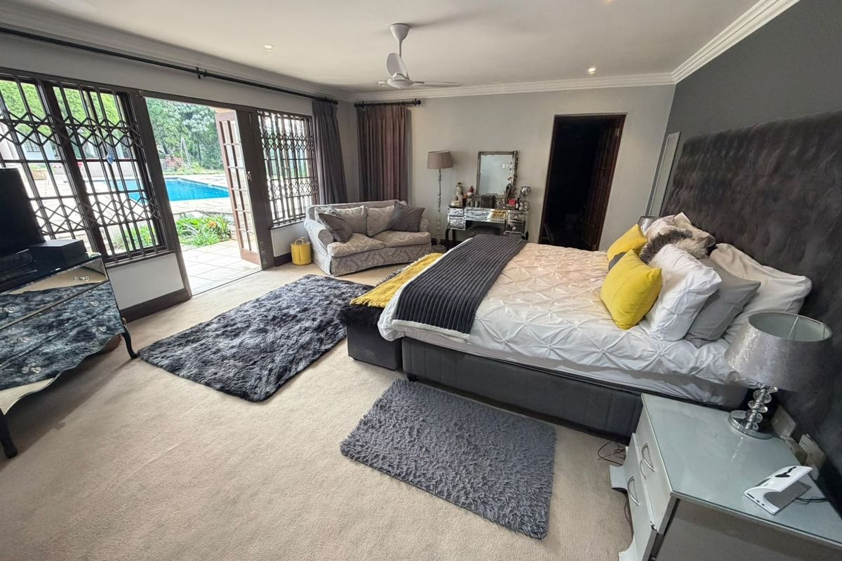 Spacious bedroom featuring neutral carpeting, recessed lighting, and sliding glass doors providing direct access to the outdoor pool area.