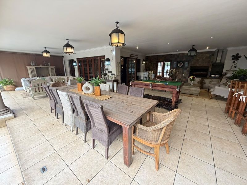 Spacious covered patio featuring tiled flooring, a built-in braai, stone feature wall, and ample space for outdoor dining and entertainment.
