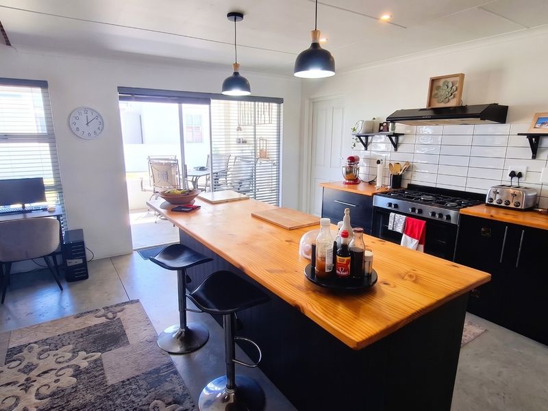 Modern open-plan kitchen featuring a large wooden island, gas hob, subway tile backsplash, and direct access to an outdoor patio area.