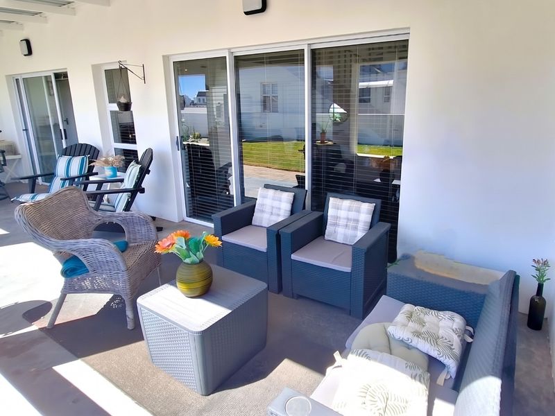 A covered outdoor patio area featuring concrete flooring and large sliding glass doors providing access to the interior living space.