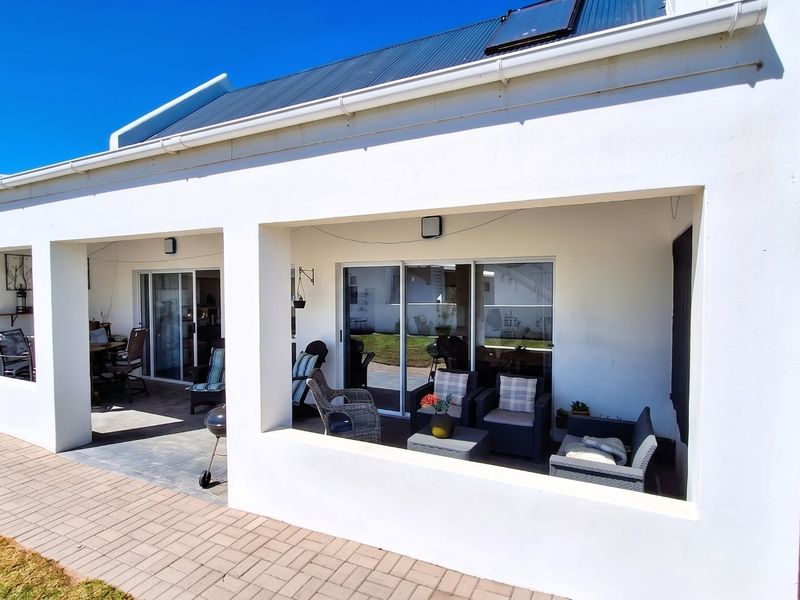 A spacious covered patio area featuring paved flooring and large sliding glass doors, providing seamless indoor-outdoor flow.