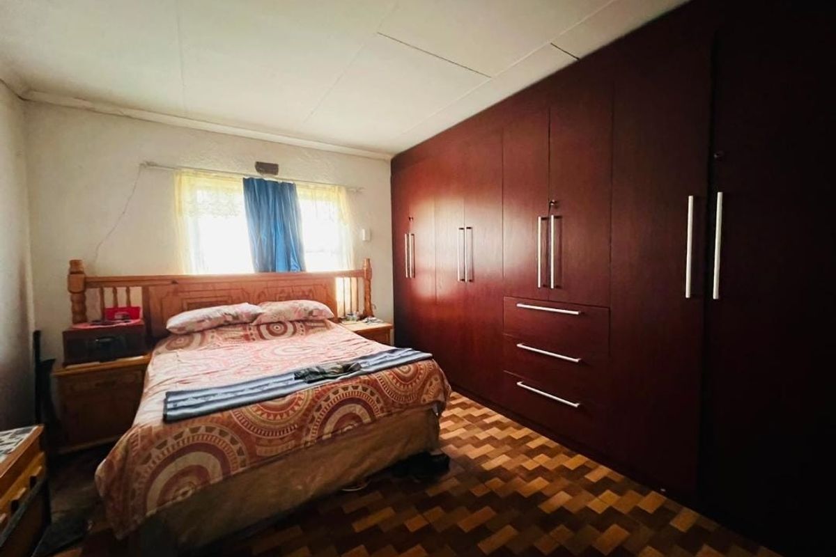 A bedroom featuring extensive built-in wooden cupboards and traditional parquet flooring, offering ample storage space and a classic layout.