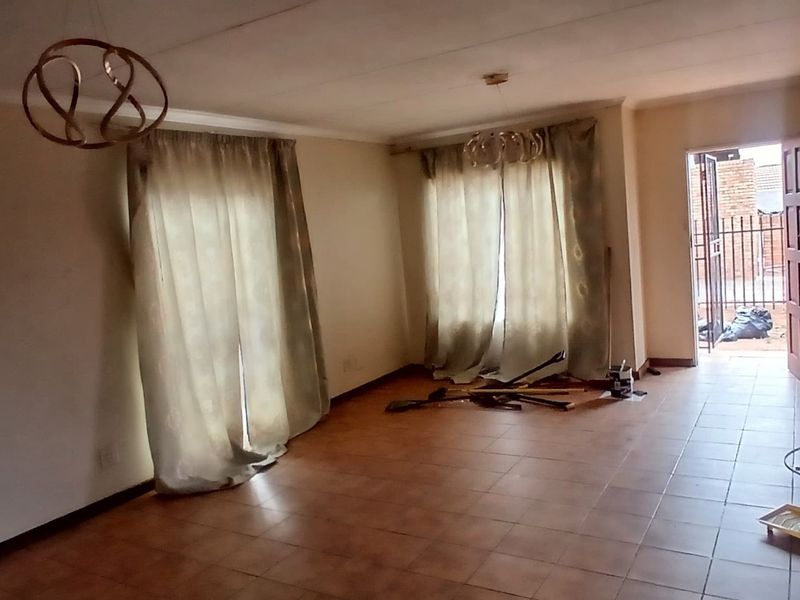 An empty living room featuring tiled flooring, coved ceilings, and direct access to an outdoor area through an external door.