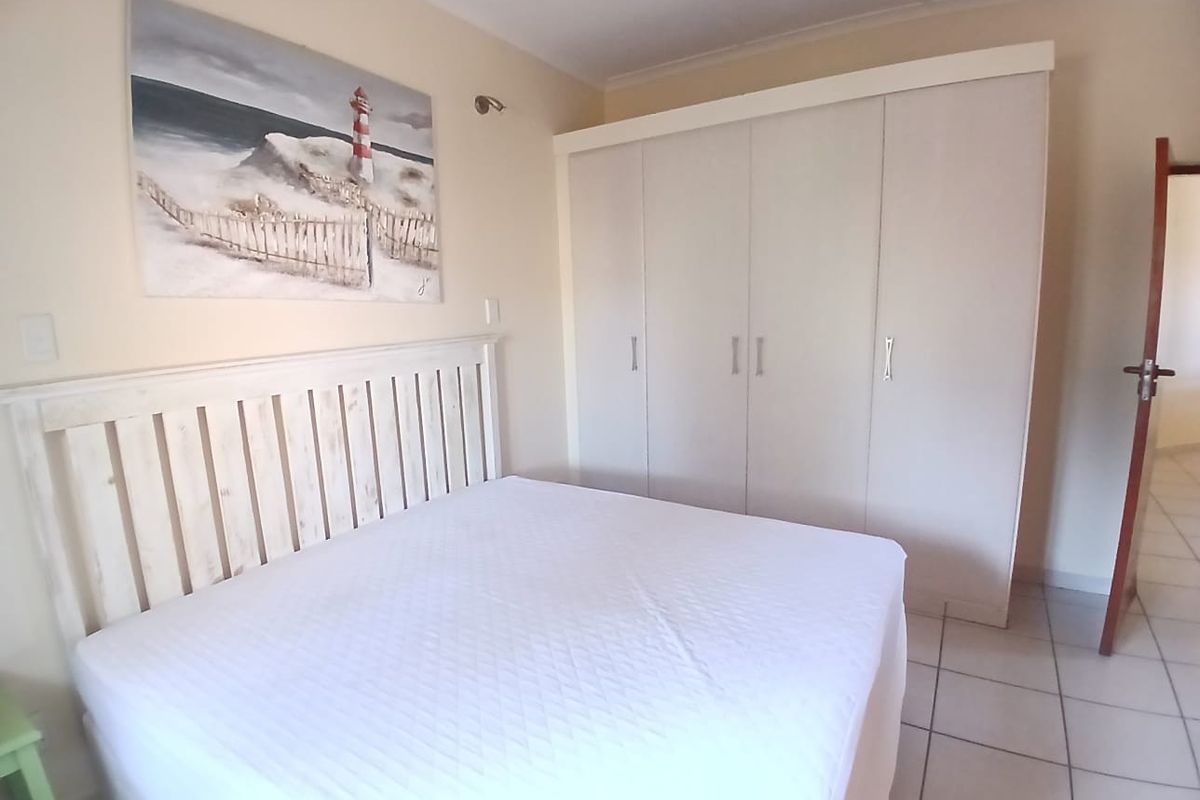 A bedroom featuring tiled flooring and a large built-in wardrobe with white cabinetry.