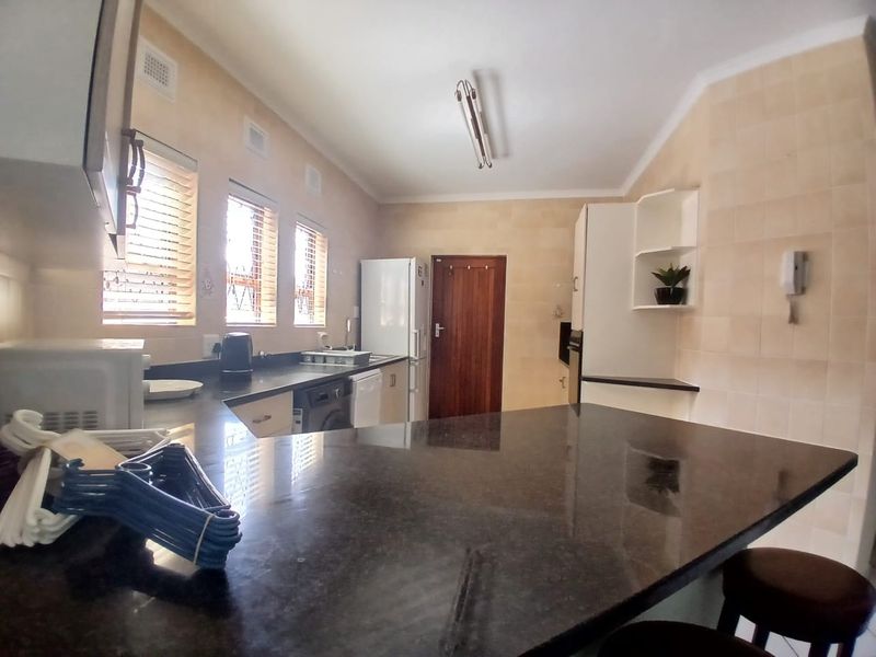 A functional kitchen featuring granite countertops, tiled wall finishes, and built-in cabinetry with a breakfast bar area.