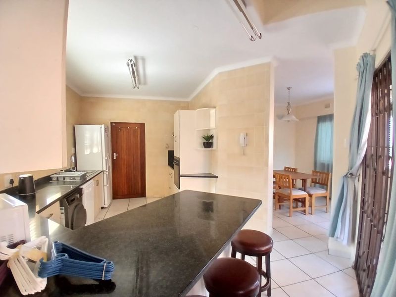 Open-plan kitchen and dining area featuring granite countertops, tiled flooring, and built-in cabinetry, providing a functional layout for daily living and dining.