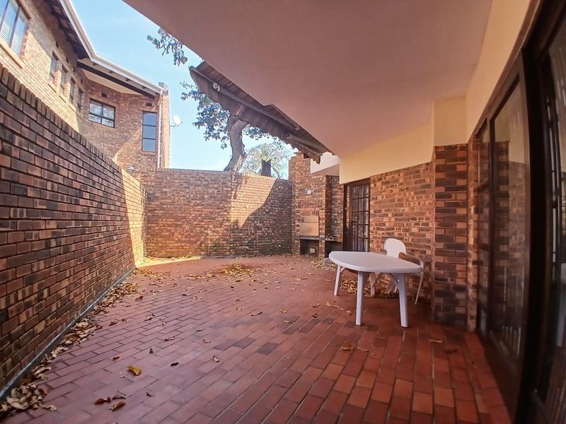 A covered outdoor patio area featuring facebrick walls, brick paving, and a built-in braai, offering a private space for outdoor entertaining.