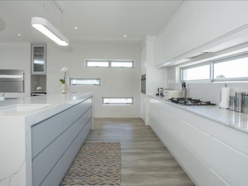 Modern kitchen featuring a large island with stone countertops, integrated gas cooktop, sleek cabinetry, and high-quality finishes throughout.