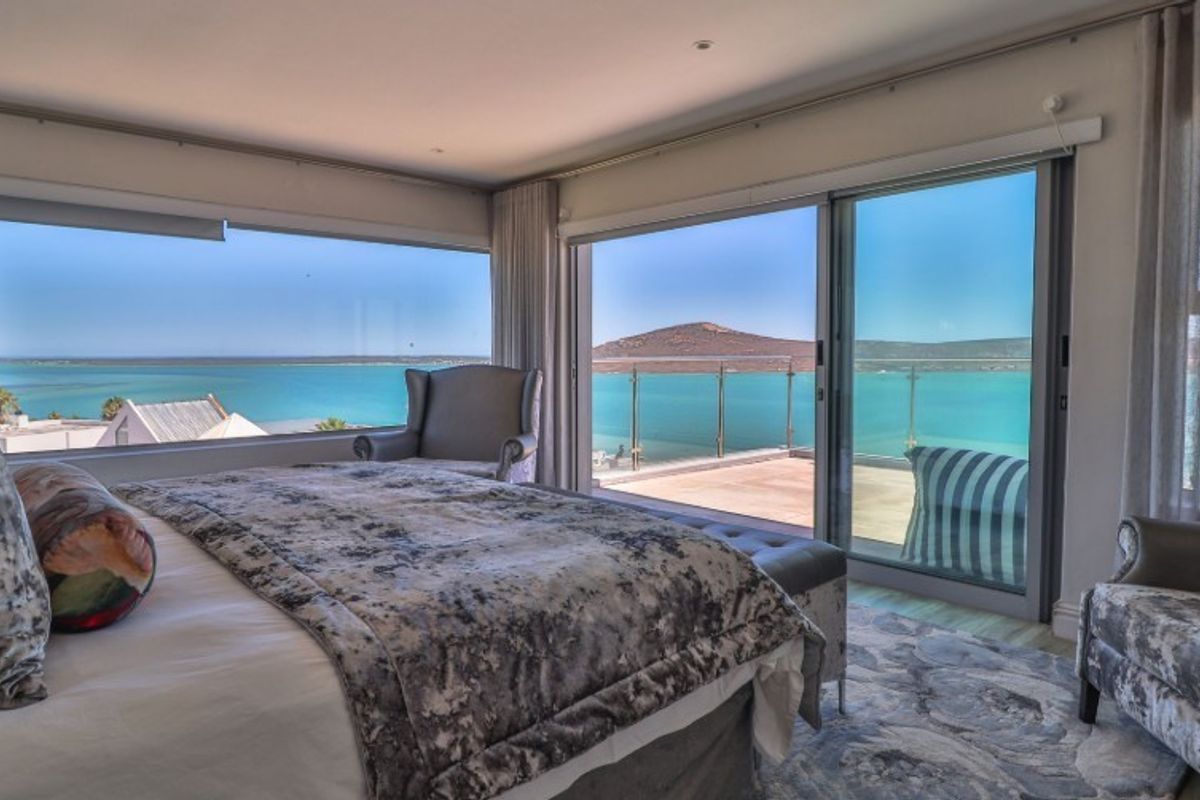 Spacious bedroom featuring expansive windows and sliding glass doors that open onto a balcony with panoramic ocean views.