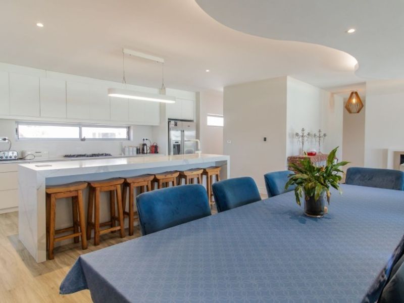 Modern open-plan living area featuring a sleek kitchen with a large island, integrated appliances, and a contemporary built-in fireplace.