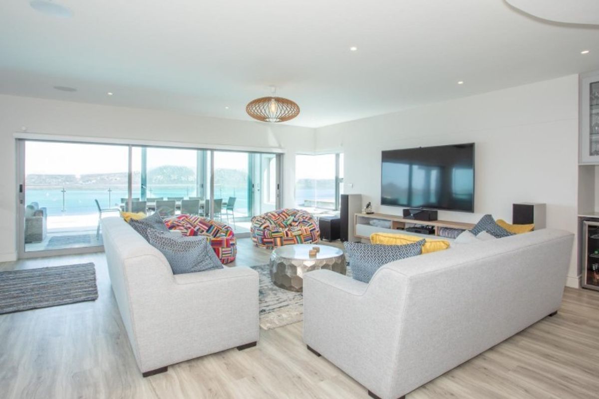 Spacious living room featuring modern laminate flooring, recessed lighting, and large sliding glass doors that open to a scenic outdoor patio area.