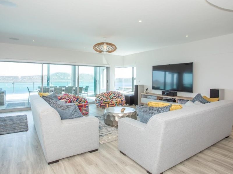 Spacious living room featuring modern laminate flooring, recessed lighting, and large sliding glass doors that open to a scenic outdoor patio area.