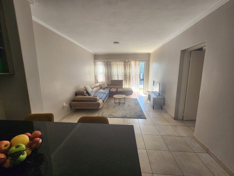 Open plan living area featuring neutral wall tones, tiled flooring, and direct access to an outdoor space through a sliding glass door.