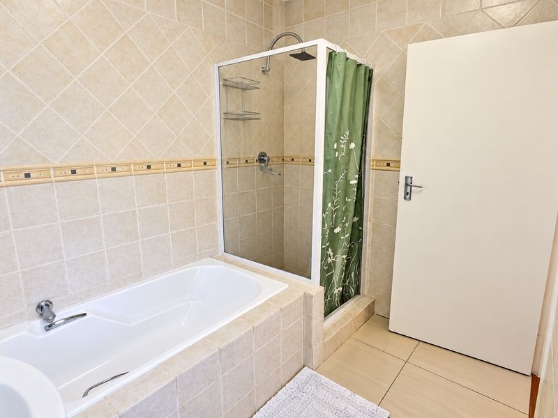 A functional bathroom featuring a built-in bathtub, a separate shower enclosure with tiled walls, and neutral floor tiling.