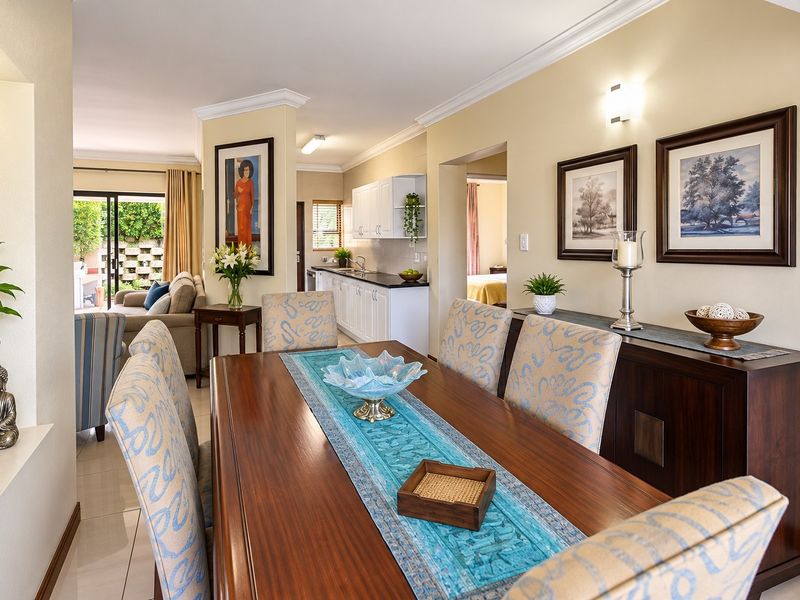 An open-plan dining and kitchen area featuring tiled floors, crown molding, and a functional kitchen layout with direct access to an outdoor patio space.