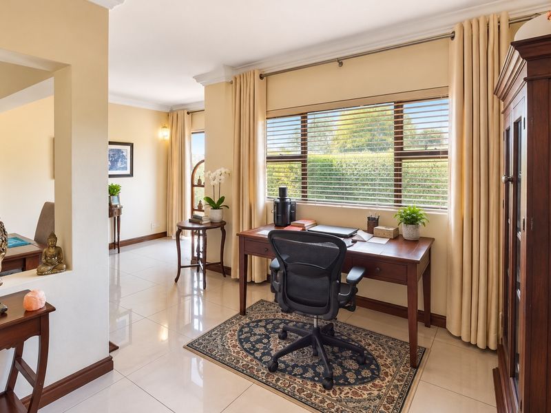 A bright and well-maintained home office space featuring polished tiled flooring, decorative cornicing, and large windows with fitted blinds.