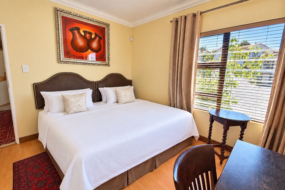 A well-maintained bedroom featuring laminate flooring, decorative cornice, and large windows with fitted blinds, offering a comfortable and bright living space.