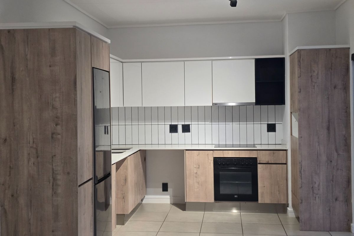 Modern kitchen featuring wood-grain and white cabinetry, integrated oven and hob, tiled backsplash, and neutral floor tiles in a clean, contemporary layout.